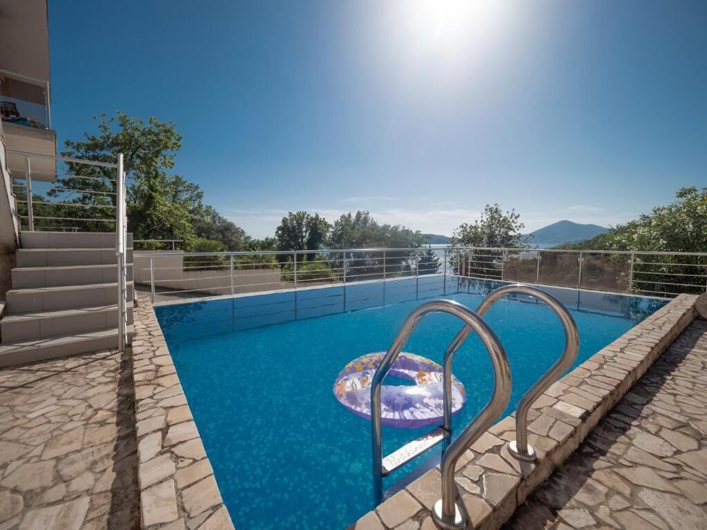 Ein Swimmingpool mit freiem Blick auf die umliegende Landschaft, darunter Bäume und ein entfernter Berg.