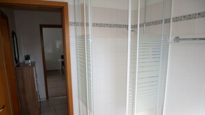 Un bagno con box doccia in vetro, pareti piastrellate e un armadietto in legno.