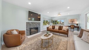 Un salon avec une cheminée, un canapé, une table basse et un téléviseur fixé au mur.