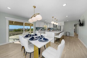 A modern kitchen with white cabinets, a central island, and a dining area with white chairs and a table set for four.