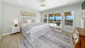 Une chambre à coucher comprenant un lit, une table de chevet et une vue sur l’extérieur grâce à une porte coulissante.