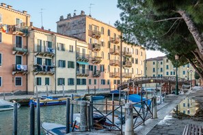 Un canal où naviguent des bateaux, un pont en bois et des bâtiments dotés de balcons.