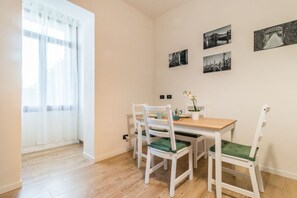 A dining area with a wooden table, white chairs with green cushions, and black-and-white photographs on the wall. - Casa di Arianna @Venice (Venezia)
