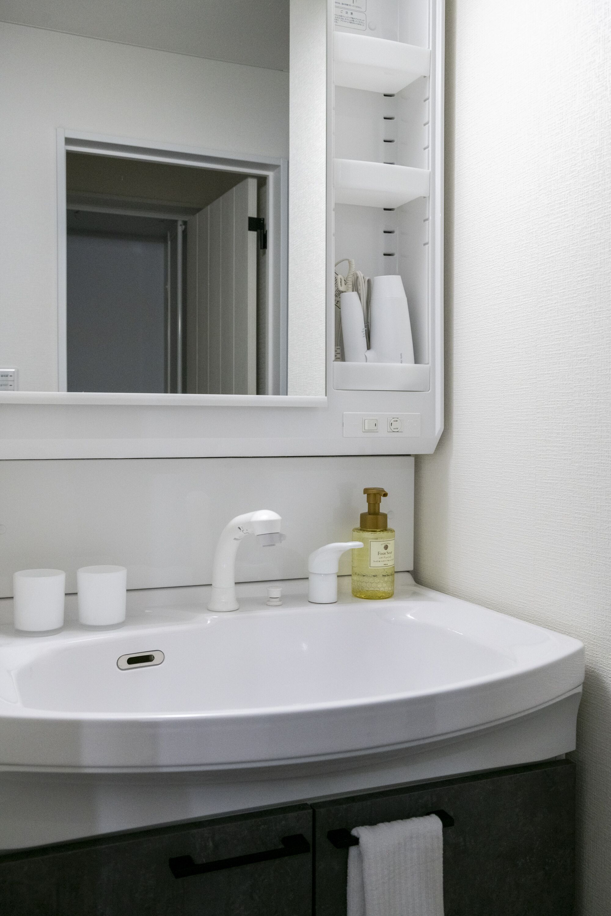 A bathroom with a white sink, a mirror, and a towel rack.