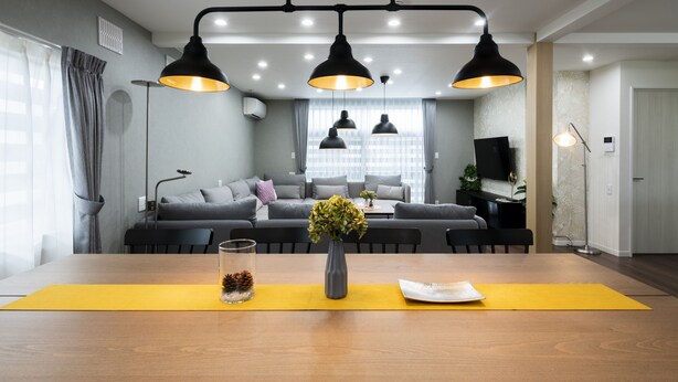 A modern living room with a dining area, grey sofas, a yellow rug, and black pendant lights. - FC Farnest Niseko (Kutchan)