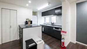 A modern kitchen with dark cabinets, a white countertop, and a fire extinguisher. - FC Farnest Niseko (Kutchan)
