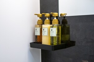Un estante con cuatro botellas de productos de cuidado corporal.