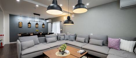 Una sala de estar moderna con un sofá seccional, una mesa de centro de madera e iluminación colgante.