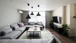 A modern living room with a grey sofa, a coffee table, and a TV on a stand. - FC Farnest Niseko (Kutchan)
