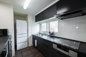 Una cocina moderna con armarios oscuros, una campana extractora de acero inoxidable, un horno empotrado y una ventana sobre el fregadero.