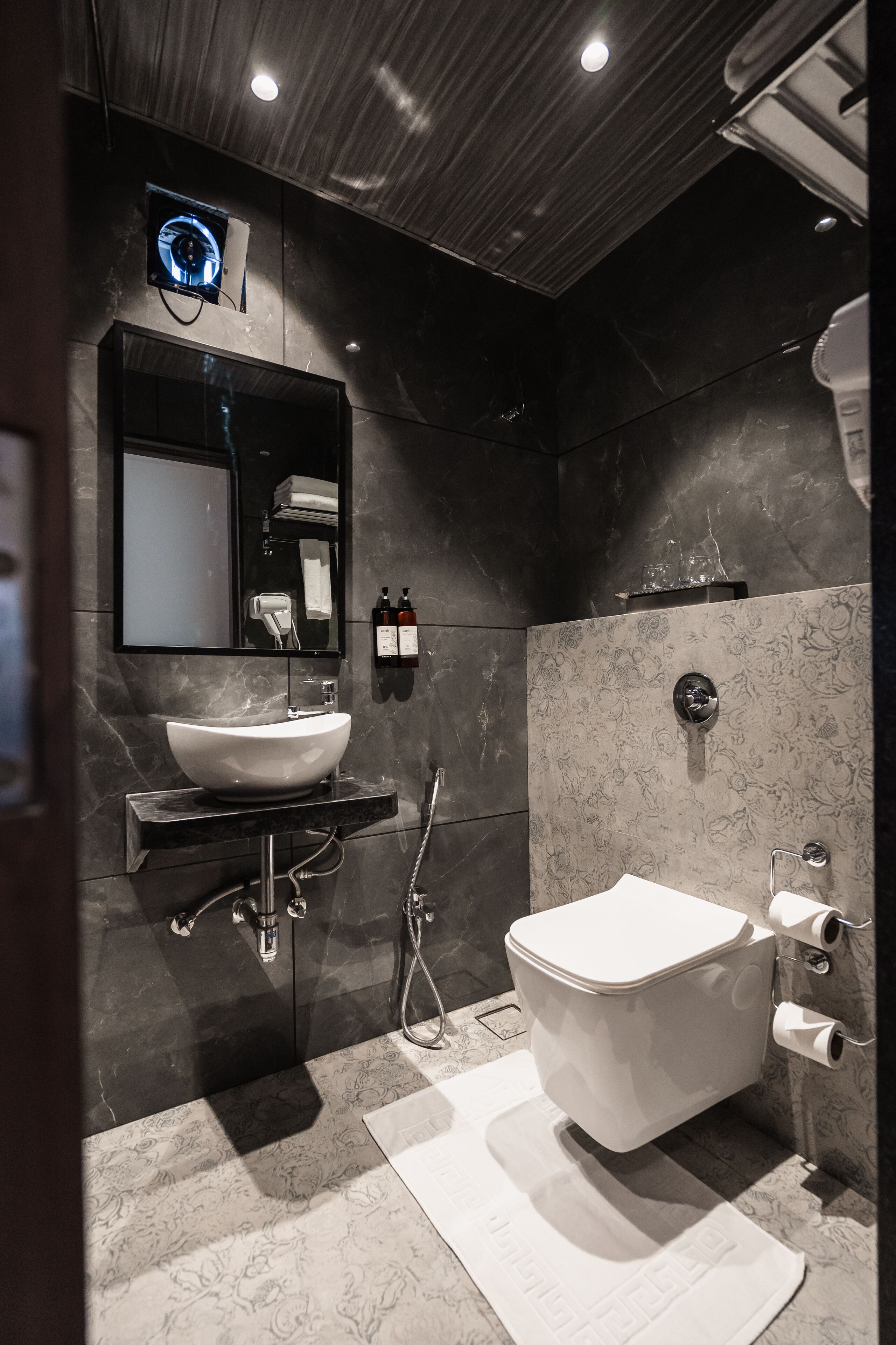 A modern bathroom with a large white sink, a mirror, a toilet, and a shower.