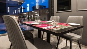 A dining area with a table set for two, chairs, and a view of the pool area. - Regenta Place Igatpuri  (Igatpuri)