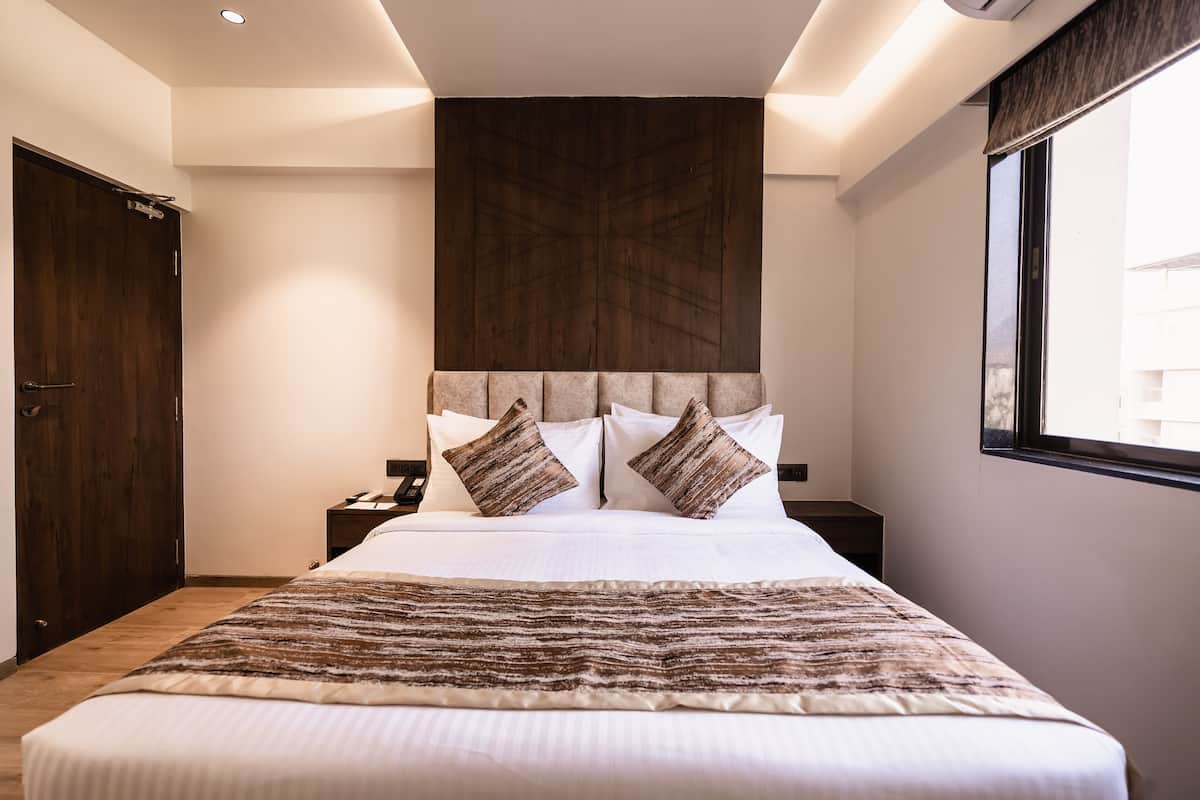 A neatly made bed with a striped blanket, a wooden headboard, and two bedside tables with lamps.