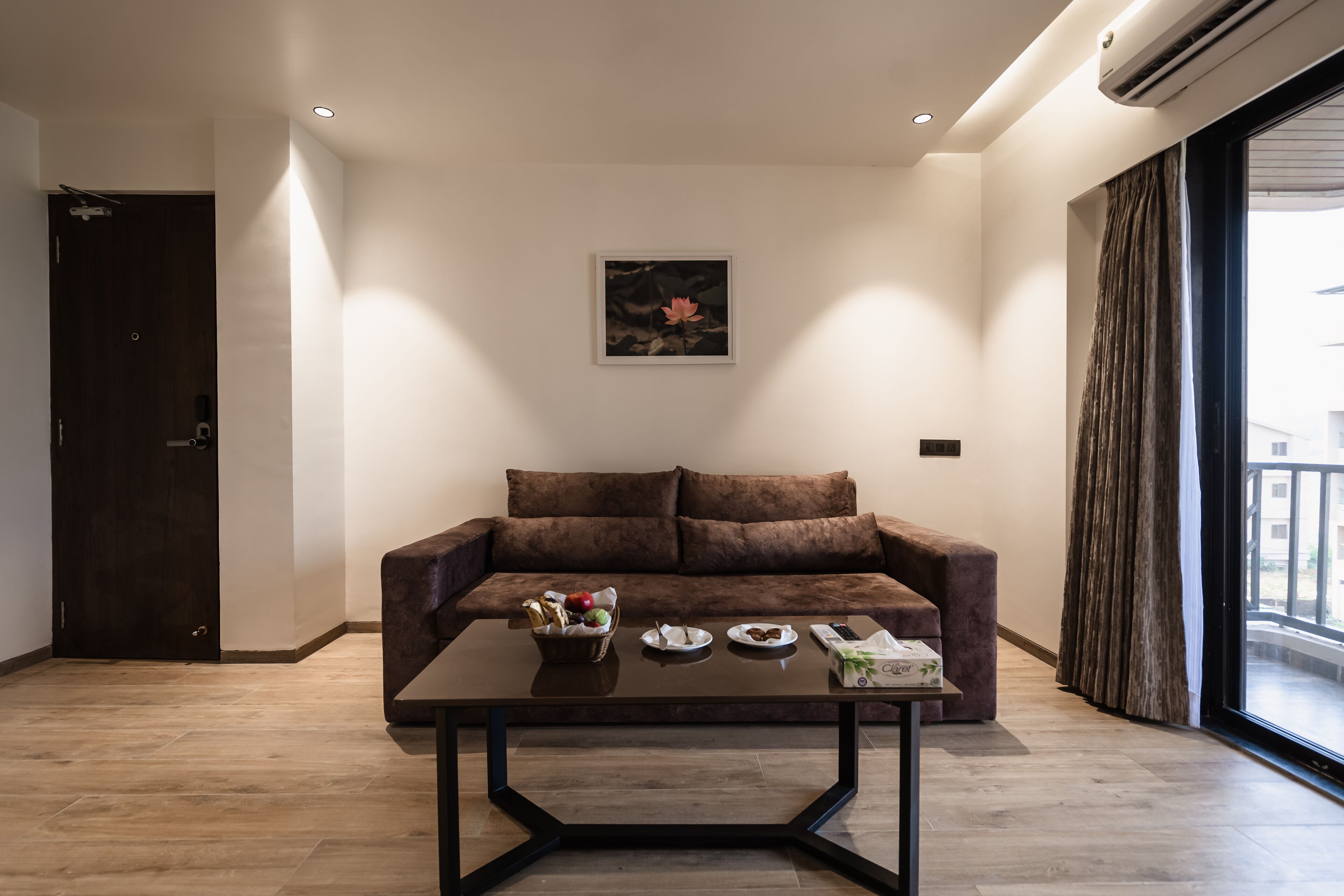Een moderne woonkamer met een bruine bank, een bijzettafeltje met eten en een schilderij aan de muur.