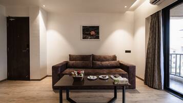 Een moderne woonkamer met een bruine bank, een bijzettafeltje met eten en een schilderij aan de muur.