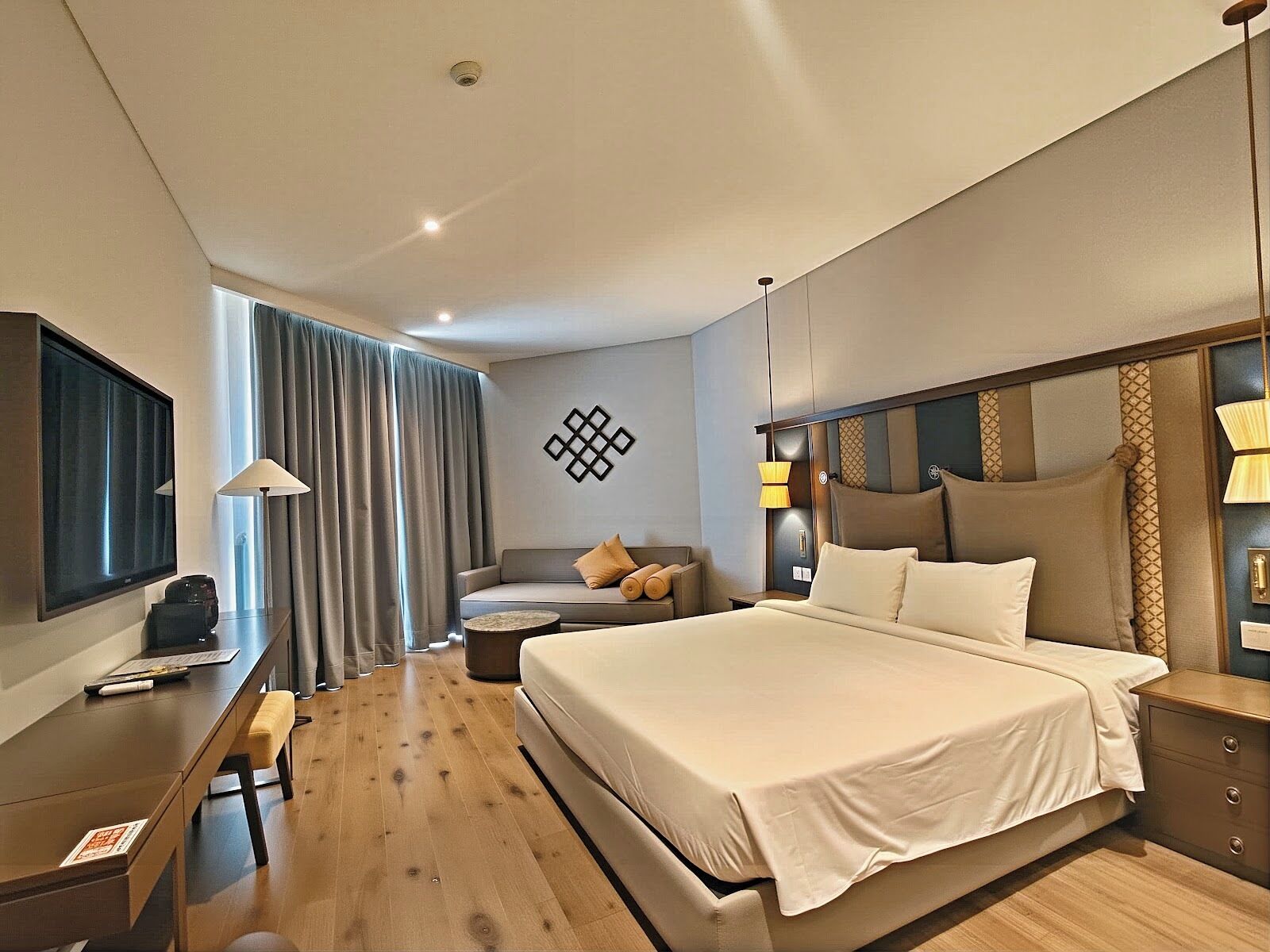 Une chambre d’hôtel moderne dotée d’un grand lit, d’un bureau, d’une chaise, d’une télévision et offrant une vue sur l’extérieur.