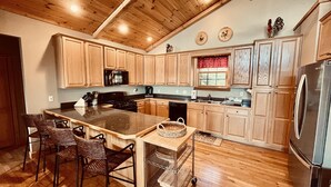 A kitchen with wooden cabinets, a central island, a stainless steel refrigerator, and a microwave.
