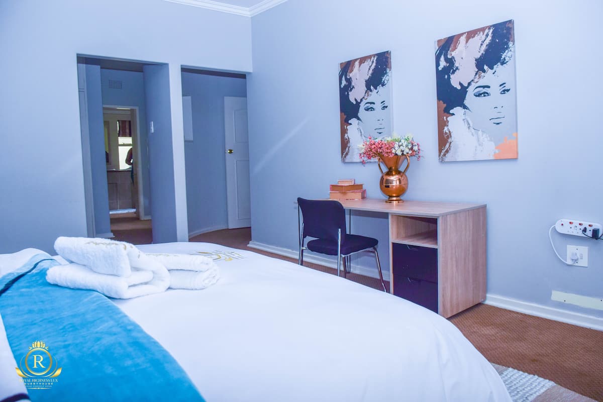 Een hotelkamer met een bed, een bureau, een stoel en twee kunstwerken aan de muur.