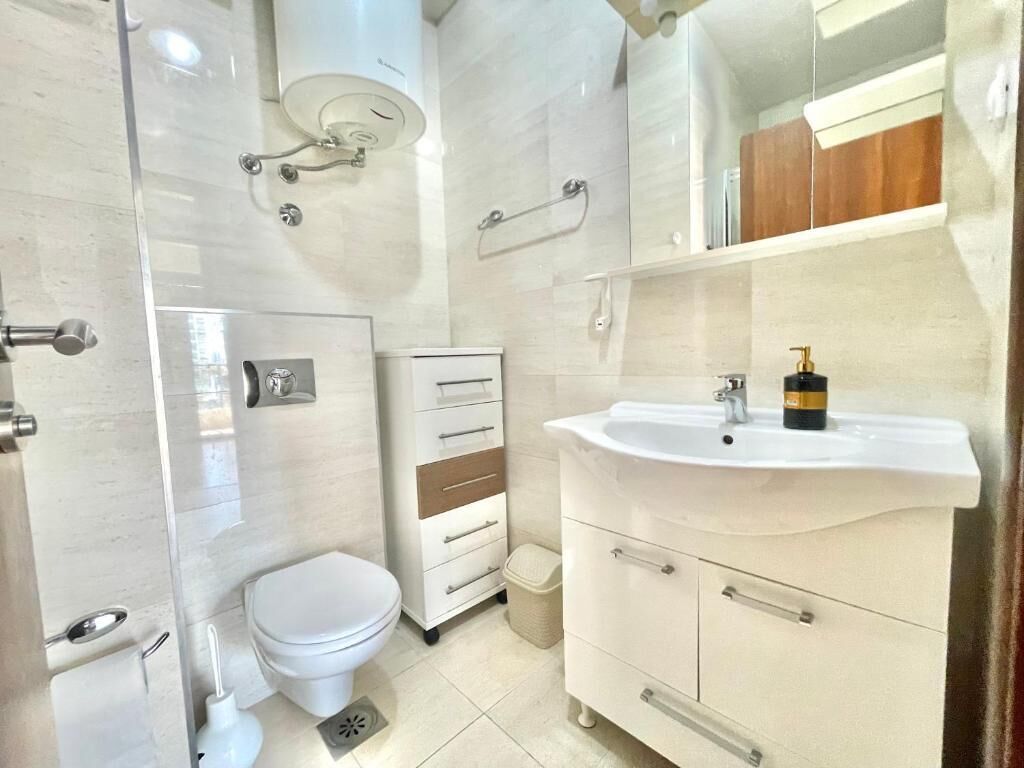 Un baño moderno con inodoro, lavabo y zona de ducha.
