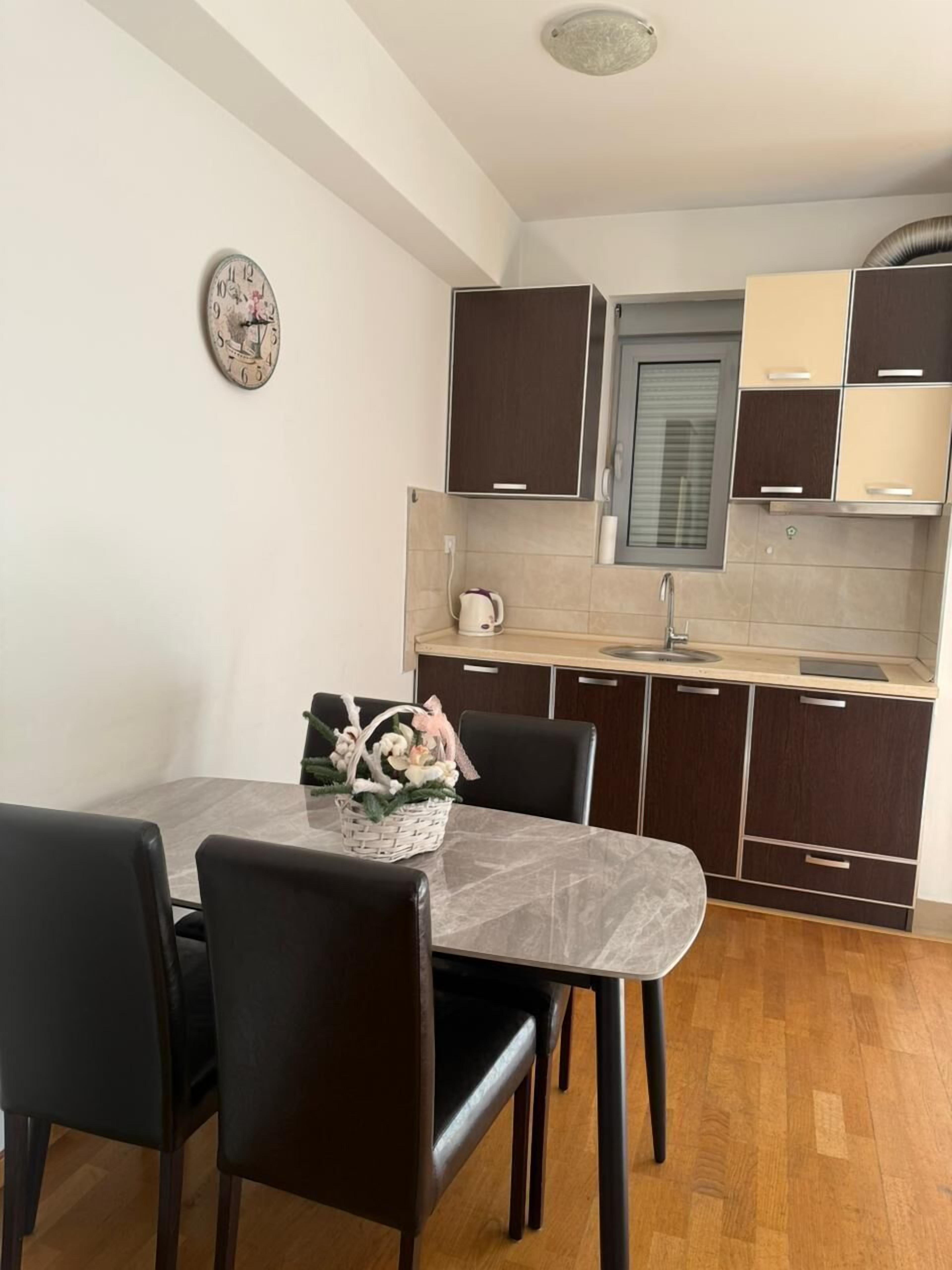 A compact kitchen with dark wooden cabinets, a marble countertop, and a dining area with a table and chairs.