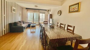 A dining area with a wooden table and chairs, a sofa, and striped wallpaper. - Comfort Apartments Aleksic (Budva)