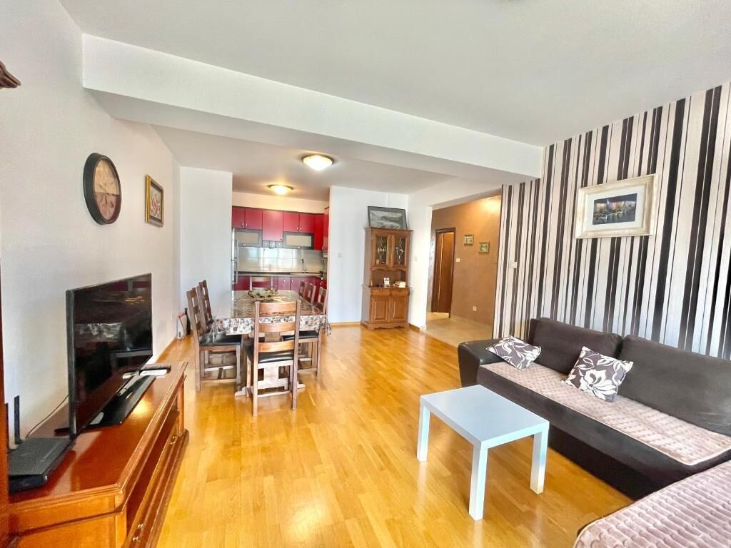 A living room with a TV, sofa, and dining area.