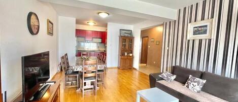 A living room with a TV, sofa, and dining area.