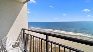 A balcony with a view of the beach and ocean.