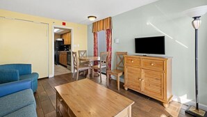 A living room with a sofa, a wooden table, a TV, and a cabinet.