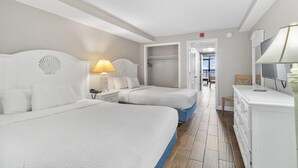 A hotel room with two beds, a desk, a chair, a TV, and a bathroom visible through an open door. - Oceanfront Suite: 2 Queens Free Breakfast 11th Flr (Myrtle Beach)