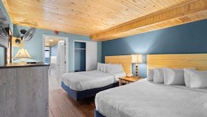 Habitación de hotel con dos camas, techo de madera y vista al mar.
