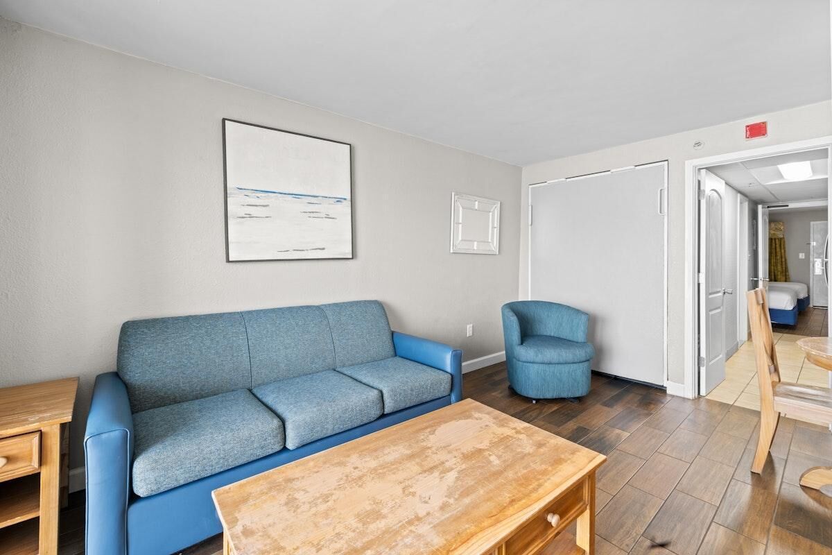 Una sala de estar con un sofá azul, una mesa de centro de madera y un sillón azul.