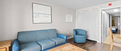 Una sala de estar con un sofá azul, una mesa de centro de madera y un sillón azul.