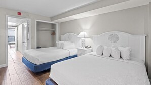 A hotel room with two beds, a walk-in closet, a bedside table with a lamp, and a view of the hallway. - Airy Oceanfront Suite with Breakfast 14th Floor (Myrtle Beach)