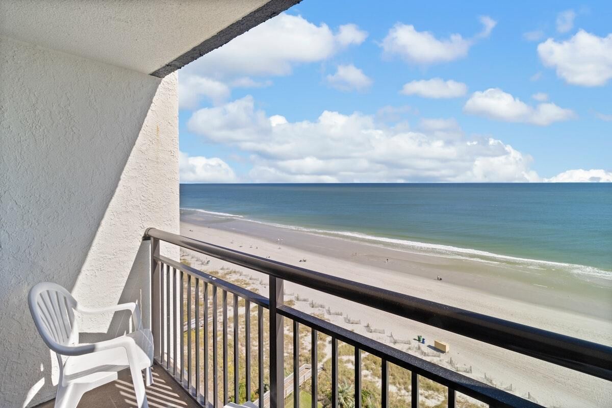 A balcony with a view of a beach and ocean.