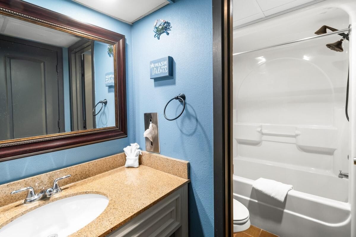 A bathroom with a sink, mirror, towel rack, and a shower area.
