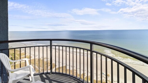 A balcony with a view of the beach and ocean.