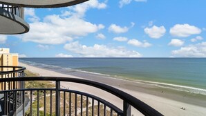 A balcony with a view of a beach and ocean.