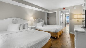 A hotel room with two beds, a walk-in closet, and a television.