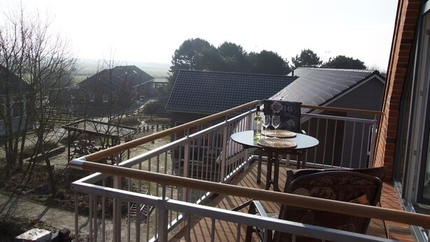 Een balkon met een tafel en stoelen, met uitzicht op een woongebied met huizen en bomen.