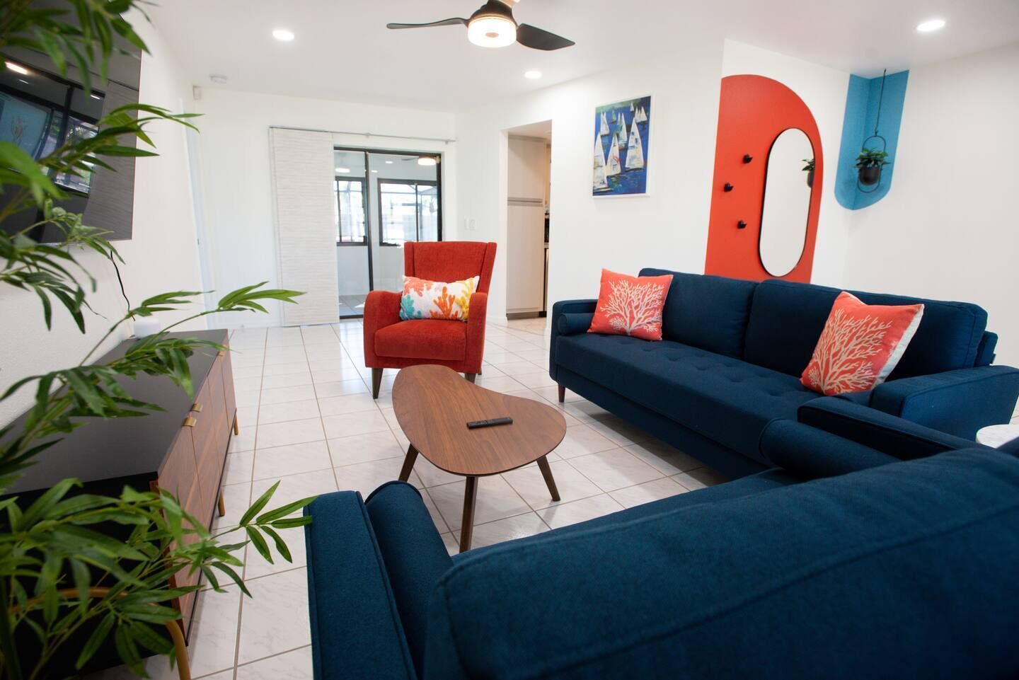Una sala moderna con un sofá azul, un sillón rojo y una mesa de centro de madera.