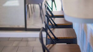 Een modern zithoekje binnen met houten stoelen en een lange tafel, waarschijnlijk in een café of restaurant.