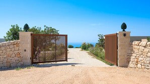 A gated entrance with a dirt path leading to a building. - Panoramic luxury villa with private pool in Sampieri - Di Casa In Sicilia (Sampieri)