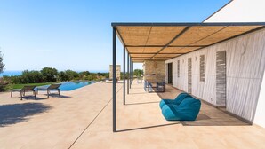 A covered outdoor area with a pool, lounge chairs, and a blue bean bag. - Panoramic luxury villa with private pool in Sampieri - Di Casa In Sicilia (Sampieri)