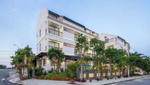A multi-story hotel with balconies, a landscaped garden, and a parked RV. - Vivi An Bang Hotel (Da Nang)