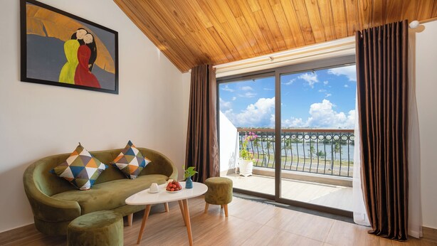 A modern living room with a green sofa, a small round table, and a painting on the wall. - Vivi An Bang Hotel (Da Nang)