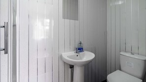 Un baño con lavamanos blanco, un espejo y un inodoro.