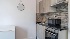 Una cocina moderna con armarios de madera, encimera negra, horno empotrado y microondas.
