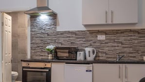 Una cocina compacta equipada con microondas, tostadora, hervidor y horno pequeño.