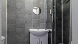 Un bagno moderno con un lavandino bianco, uno specchio e una cabina doccia in vetro.